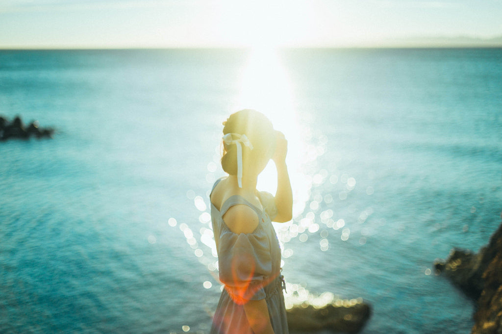 夕日に照らされた海をみる女性
